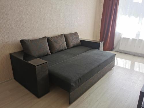 a black couch in a room with a window at Kakadu apartments in Sumy