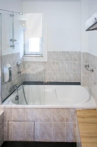 a white bath tub in a bathroom with a window at Le Cotentin Appart'hôtels & Restaurant le Cot' in Portbail