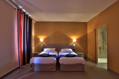 a bedroom with two beds and a walk in shower at Logis auberge restaurant Du Vigneron in Cucugnan