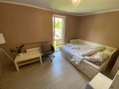 a bedroom with a bed and a chair and a window at Willa nad Sołą guest house in Oświęcim