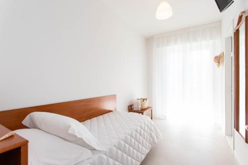 a white bedroom with a bed and a window at Hotel Mirafiori in Lido di Jesolo