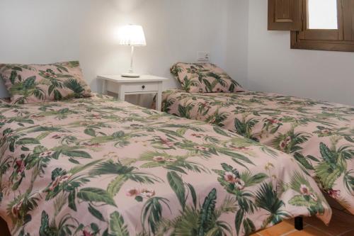 1 dormitorio con 2 camas y mesa con lámpara en CASA RURAL ADUANA, en Rubielos de Mora