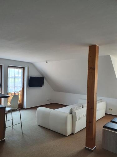 a white bed in a room with a table and a chair at Ferienwohnung im Schwarzwaldhaus in Behla