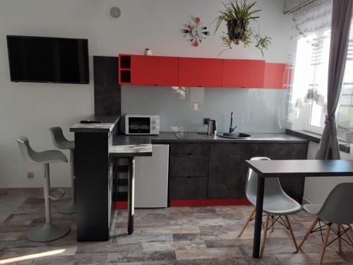 a kitchen with red cabinets and a table and chairs at Apartamenty Róża Wiatrów in Solec-Zdrój