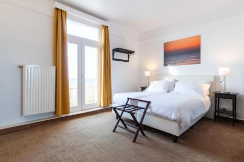 a bedroom with a white bed and a window at Thermae Palace in Ostend