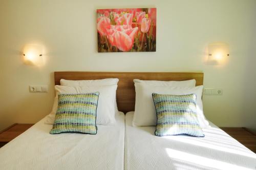 a bed with two pillows and a painting on the wall at Villa Verano in Cala Galdana