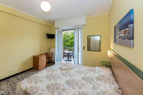 a bedroom with a bed and a desk and a window at Villa Adriana in Pietra Ligure