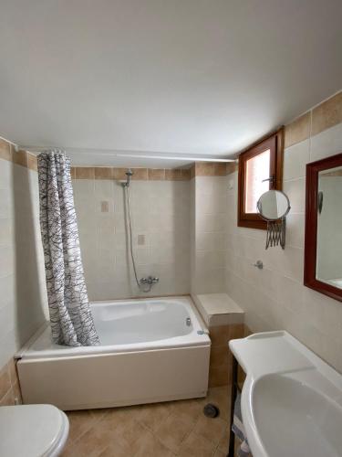 a bathroom with a tub and a toilet and a sink at Amazones Village Suites in Hersonissos