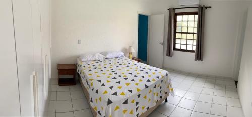 um quarto com uma cama com um edredão amarelo e branco em Condomio Coqueiros Residence em Salvador
