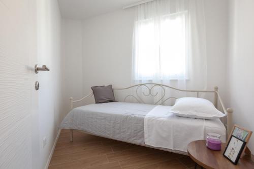 a bedroom with a bed with a window and a table at IvMaLu Apartments in Tučepi