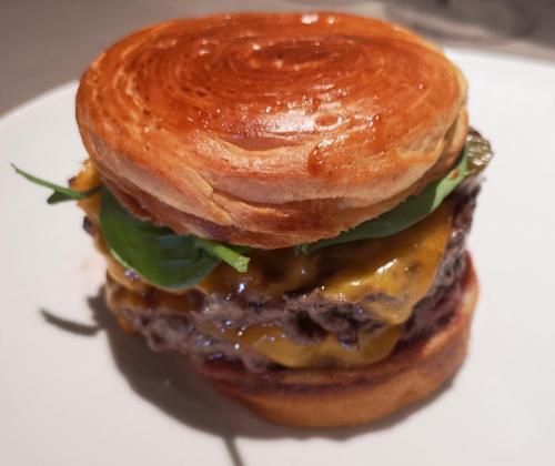 a hamburger with cheese and lettuce on a white plate at Campanile Toulouse Purpan in Toulouse