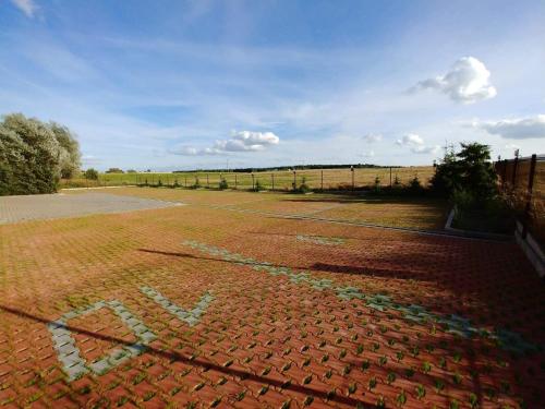 a tennis court with a fence in a field at Gościniec Piast Pokoje i Camper Park in Brzeźno