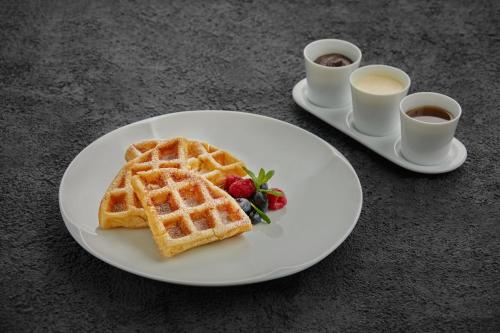 a white plate with waffles and two cups of coffee at Niccolo Suzhou in Suzhou