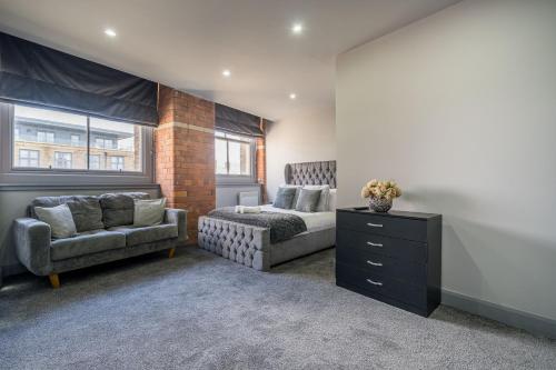 a bedroom with a bed and a couch and a chair at Hotl Aparts Huddersfield Central in Huddersfield