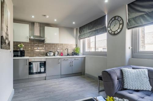 eine Küche mit einem Sofa und einer Uhr an der Wand in der Unterkunft Hotl Aparts Huddersfield Central in Huddersfield