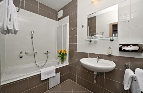 a bathroom with a sink and a bath tub at LH Parkhotel Hluboka Nad Vltavou Congress & Wellness in Hluboká nad Vltavou