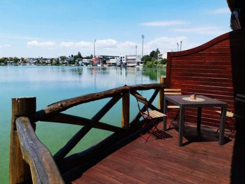 a wooden deck with a table and a bench on the water at Senec vilka na jazere in Senec