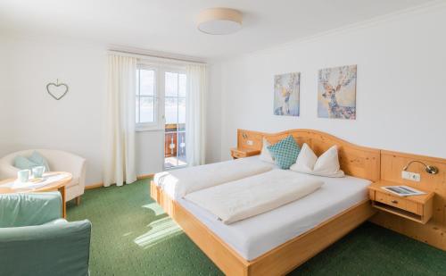 a bedroom with a large bed and a chair at Hotel Garni Buchinger in St. Wolfgang