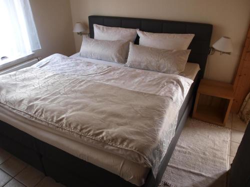 1 cama grande con sábanas y almohadas blancas en Ferienwohnung Drechsel en Olbernhau
