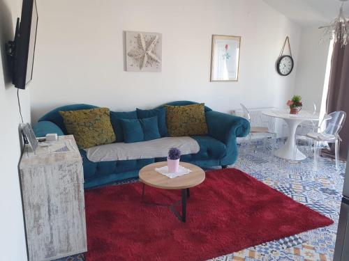 a living room with a blue couch and a red rug at Muring Apartments in Tribunj