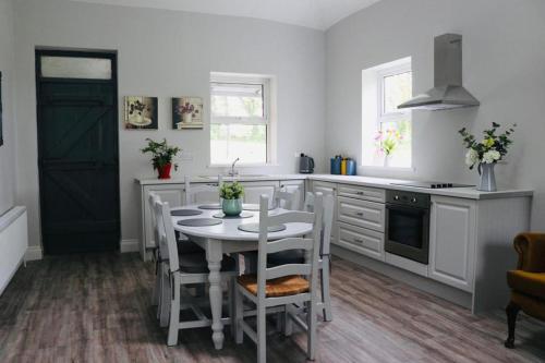 a white kitchen with a table and chairs in it at WILLOW COUNTRY COTTAGE in Killarney