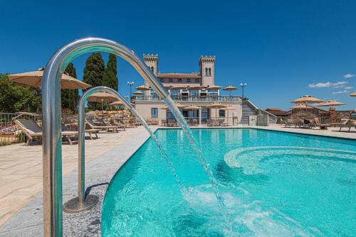 a pool with a water fountain in front of a building at Castello Bonaria Wine & Spa Resort in Campiglia Marittima