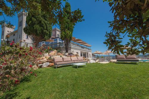 twee banken in het gras voor een huis bij Castello Bonaria Wine & Spa Resort in Campiglia Marittima