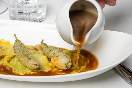 a person drizzling sauce onto a plate of food at Castello Bonaria Wine & Spa Resort in Campiglia Marittima