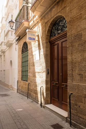a brick building with a wooden door on a street at Hostal Colón Don Miguel in Cádiz