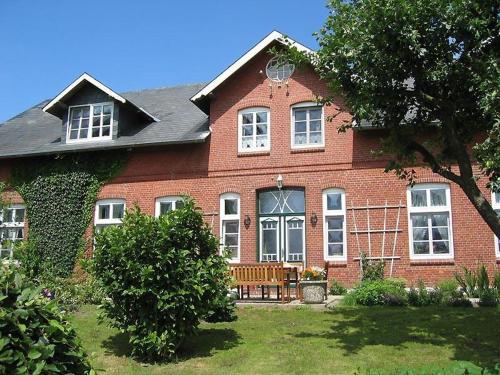 a red brick house with a bench in the yard at Der Schwalbenhof in Tetenbüll