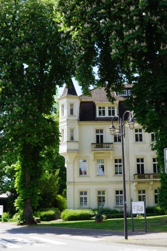 a large white building with a black roof at Monteurwohnungen in der Residenz am Kurpark in Bad Rothenfelde