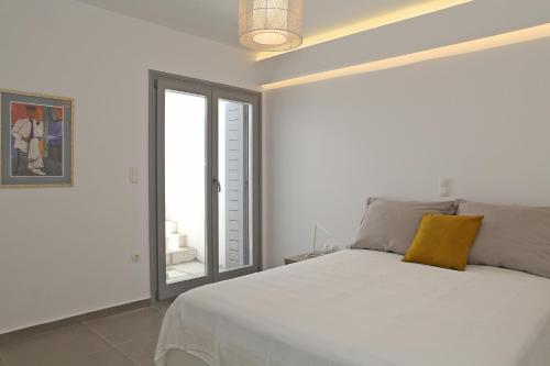a bedroom with a white bed with a yellow pillow on it at Harma Villas in Andros