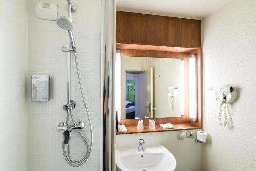 La salle de bains est pourvue d'une douche et d'un lavabo. dans l'établissement Campanile Toulouse Purpan, à Toulouse