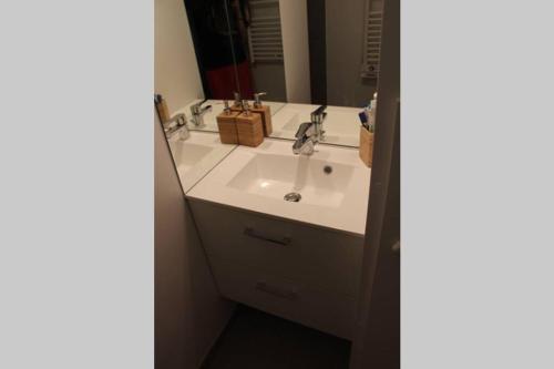 Un baño con un lavabo blanco y un espejo. en Pampita, en Villers-sur-Mer