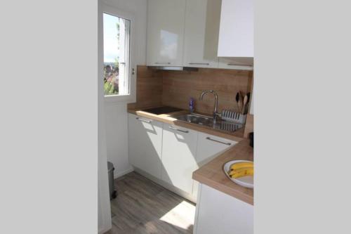une cuisine avec des armoires blanches, un évier et une fenêtre dans l'établissement Pampita, à Villers-sur-Mer