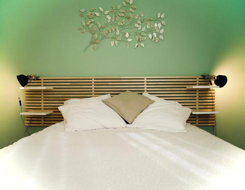 1 cama con almohadas blancas y una pintura en la pared en Rives Occitanes, Appartement Toulouse Purpan en Toulouse