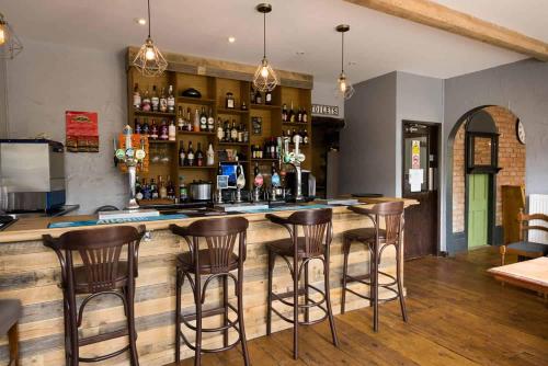 a bar with wooden counter and stools in a room at Swiss Guest House in Castleton