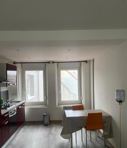 - une cuisine avec 2 fenêtres, une table et des chaises dans l'établissement Studio Bohème, à Boulogne-sur-Mer