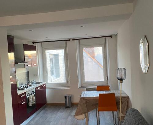 a small kitchen with a table and two windows at Studio Bohème in Boulogne-sur-Mer