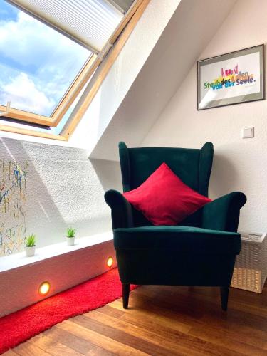 a living room with a green chair with a red pillow at Lilis kleines Hotel in Münster