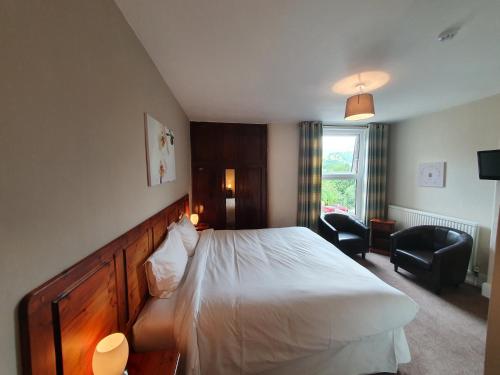 a hotel room with a bed and two chairs at Swiss Guest House in Castleton