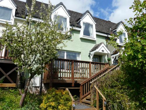 a large green house with a wooden deck at Tweed Cottage in Jedburgh