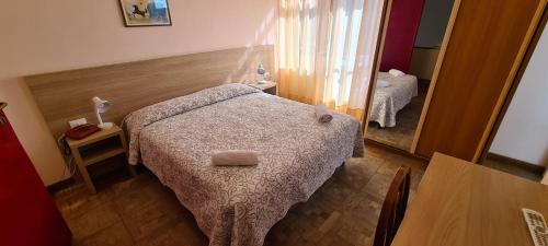 a small bedroom with a bed and a mirror at Hotel Colibrì in Finale Ligure