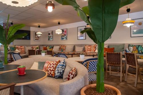 a waiting room with tables and chairs and a plant at Novotel Suites Nice Airport in Nice
