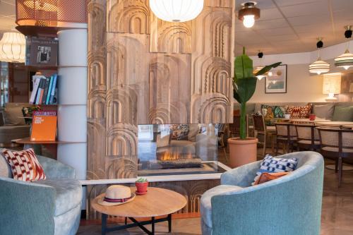 a lobby with two blue chairs and a fireplace at Novotel Suites Nice Airport in Nice