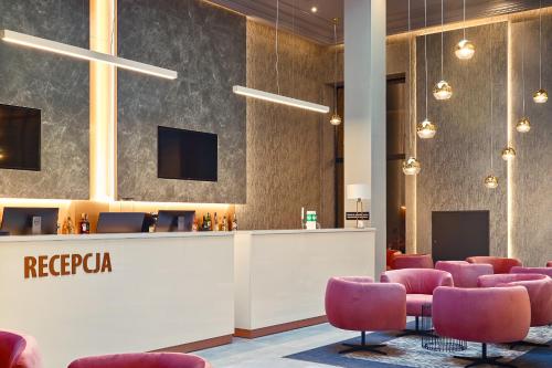 a lobby with a reception desk and pink chairs at Grand Focus Hotel Szczecin in Szczecin