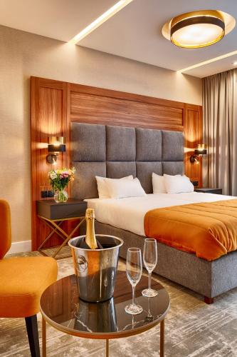a hotel room with a bed and two wine glasses on a table at Grand Focus Hotel Szczecin in Szczecin