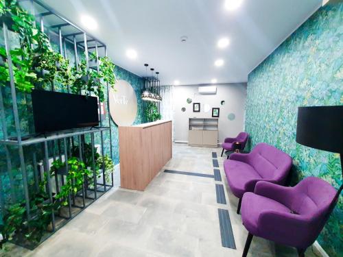 een lobby met paarse stoelen en een tv en planten bij VerTe in Techirghiol