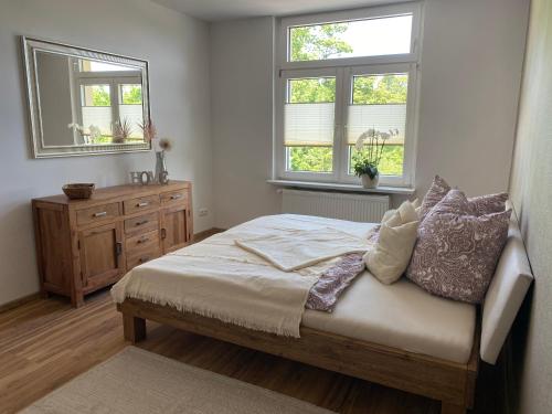 a bedroom with a bed with two windows and a dresser at Ferienwohnung Bergblick in Thale