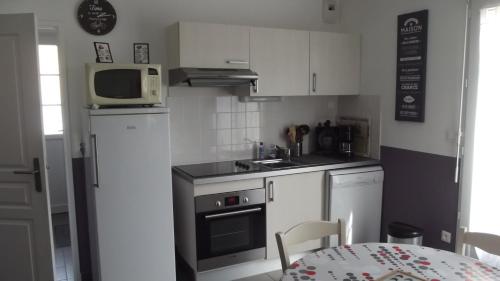 - une petite cuisine avec des placards blancs et un four micro-ondes dans l'établissement Les Pluviers en Baie, à Saint-Valery-sur-Somme